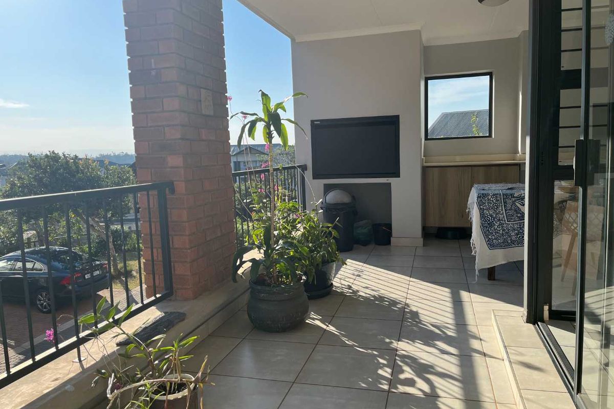 Covered balcony featuring a built-in braai, tiled flooring, and a brick pillar, offering an outdoor entertainment space with views.