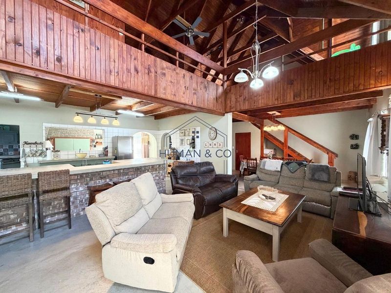 Spacious open-plan living area featuring a double-volume timber ceiling, mezzanine level, and a rustic brick breakfast bar connecting to the kitchen.