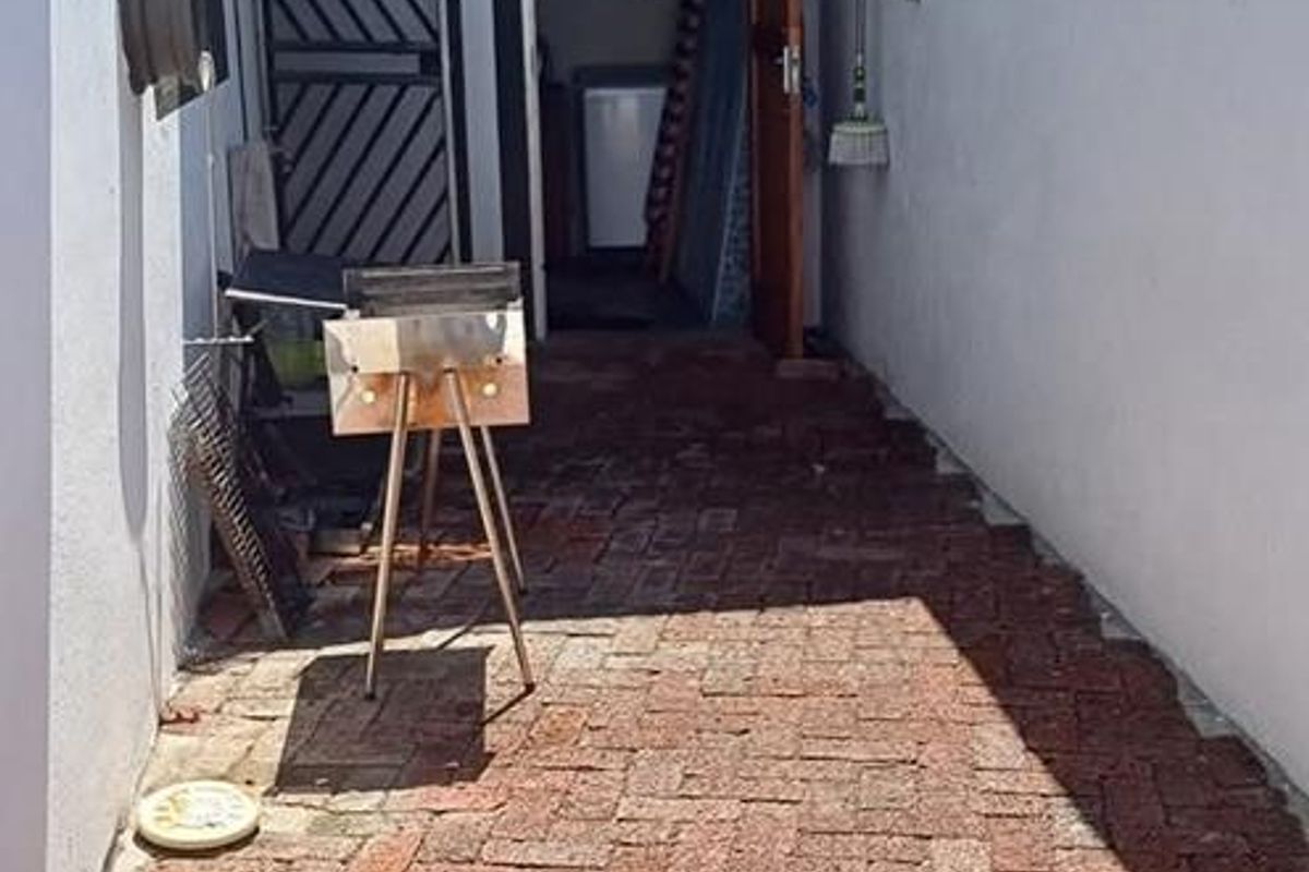 A paved side courtyard or utility area featuring a covered entrance leading to a secondary storage or laundry space.