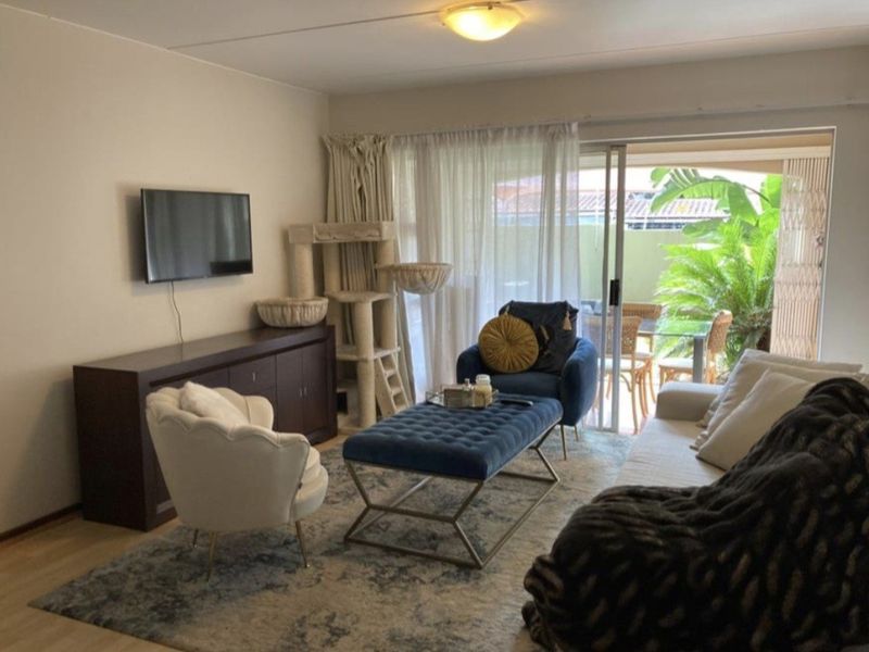 A comfortable living room featuring laminate flooring and a large sliding glass door that provides natural light and access to the patio area.