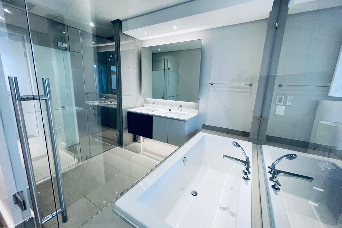 Modern bathroom featuring a double vanity, glass-enclosed shower, and a sleek freestanding bathtub with high-quality finishes and recessed lighting.