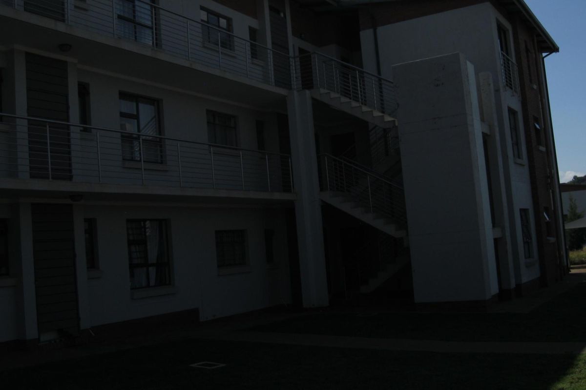 Exterior view of a multi-story apartment building featuring external staircases, metal balustrades, and paved walkways.