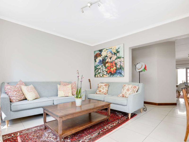A bright and well-maintained living room featuring neutral wall tones, tiled flooring, and coved ceiling details, offering a comfortable and inviting living space.