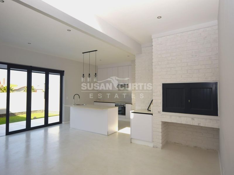 Spacious open-plan living area featuring a modern kitchen with island, built-in fireplace, and large sliding doors leading to the outdoor space.