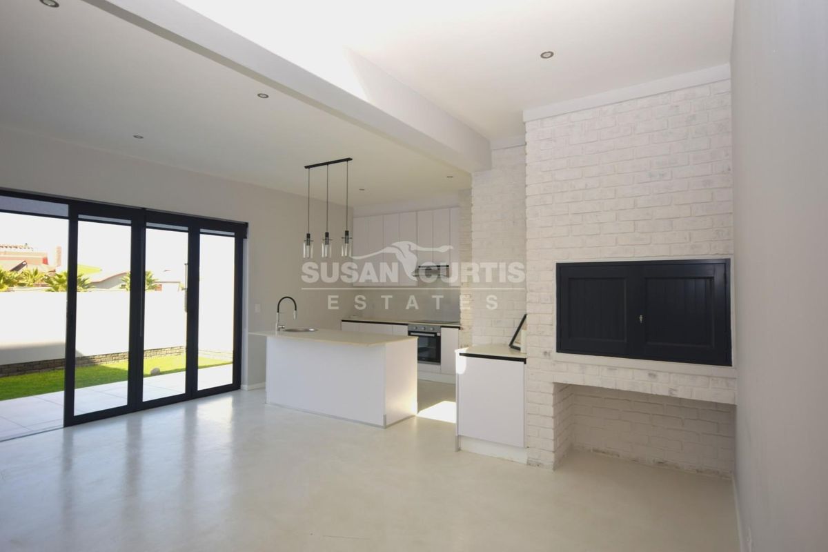 Spacious open-plan living area featuring a modern kitchen with island, built-in fireplace, and large sliding doors leading to the outdoor space.