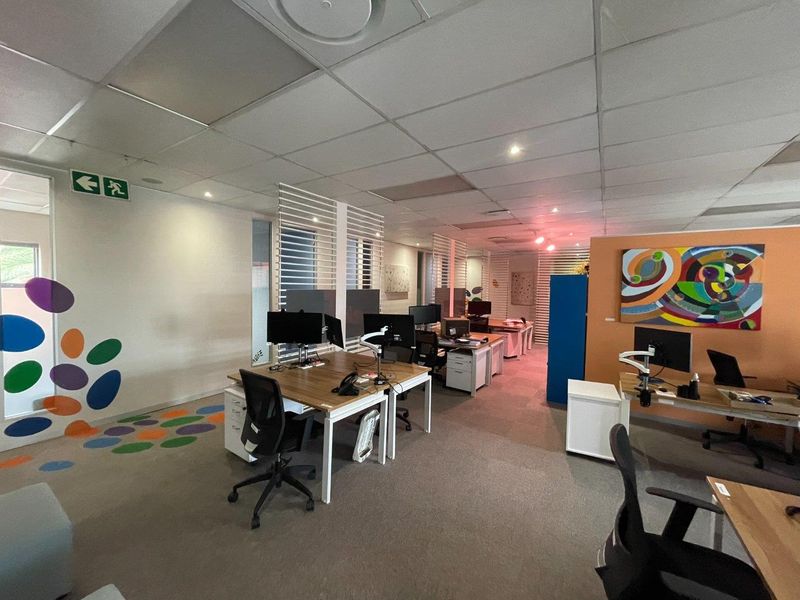 Open-plan office space featuring a suspended ceiling, recessed lighting, and carpeted flooring with integrated partition screens for workspace separation.