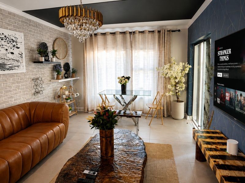 A well-appointed living room featuring an exposed brick accent wall, tiled flooring, and a sliding glass door providing natural light.
