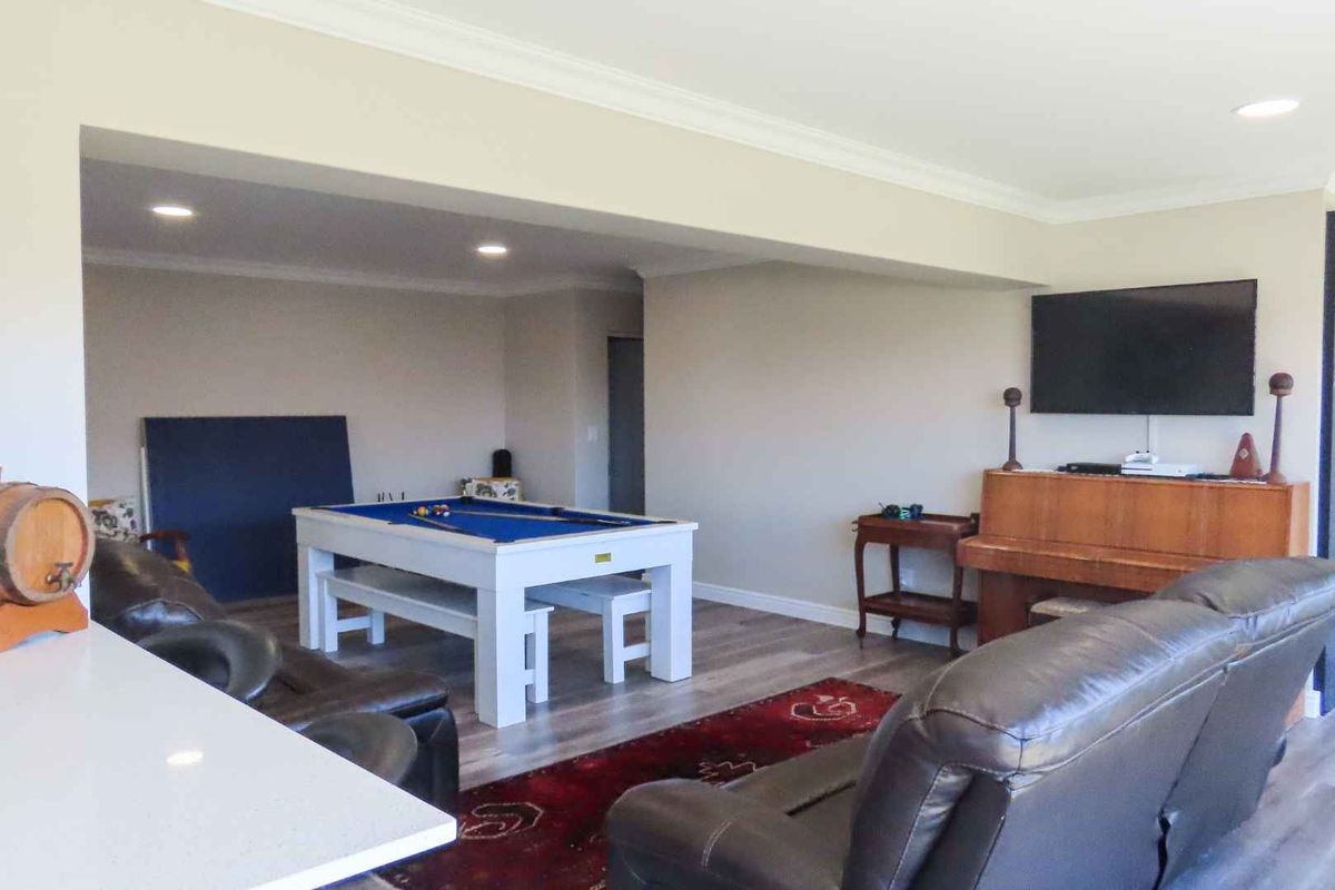 Spacious living area featuring modern laminate flooring, recessed downlighting, and crown molding, currently utilized as a multi-purpose entertainment and recreation space.