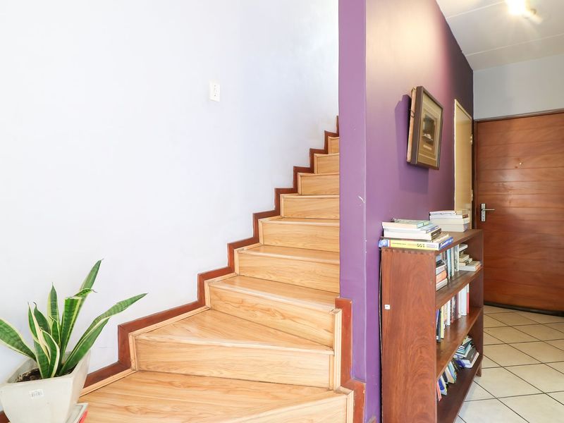 Entrance area featuring a wooden staircase and tiled flooring, leading to a solid wood front door.