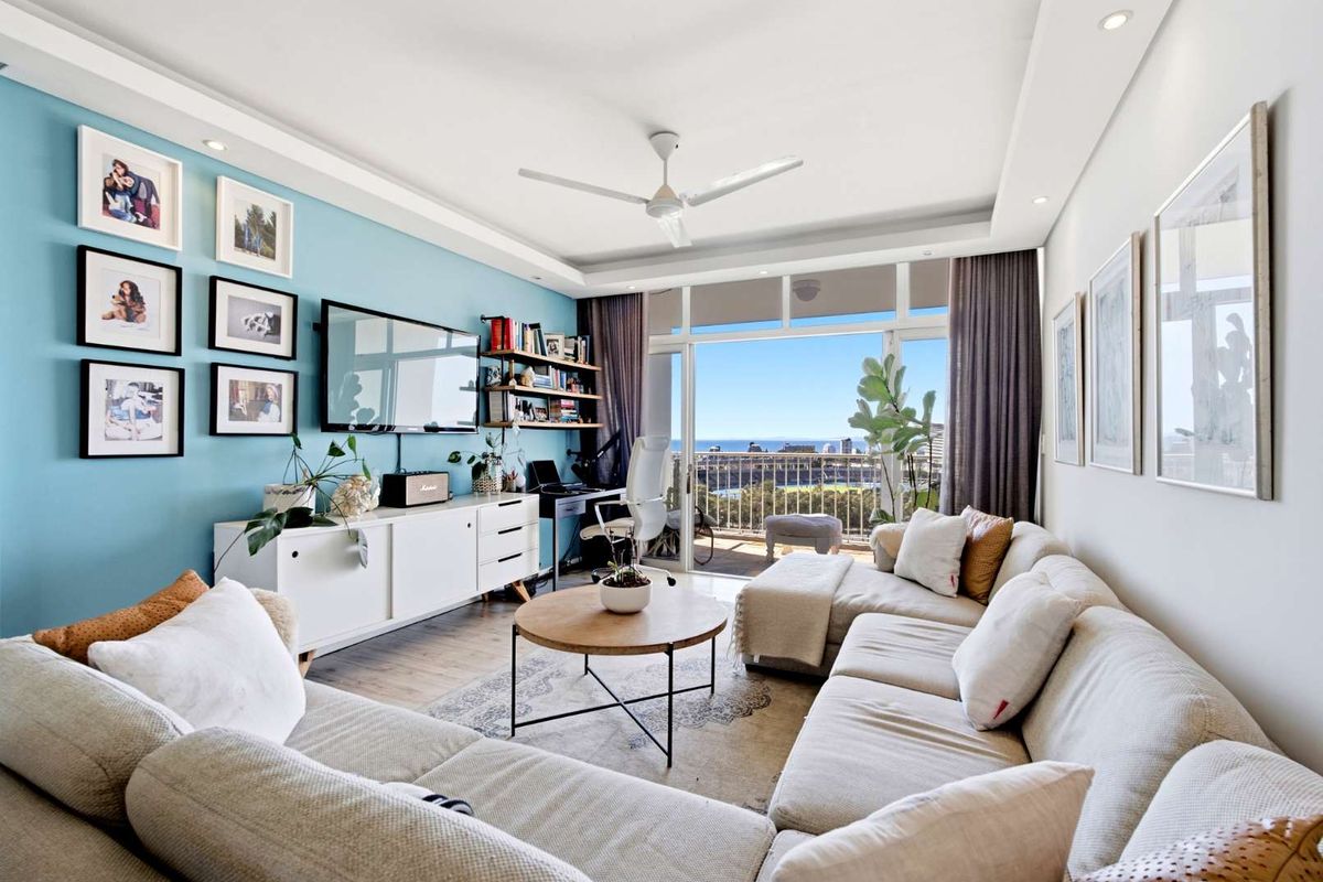 Bright and modern living room featuring laminate flooring, recessed lighting, a ceiling fan, and direct access to a balcony with scenic views.