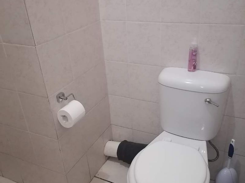 A functional bathroom featuring tiled walls and flooring with a standard toilet installation.