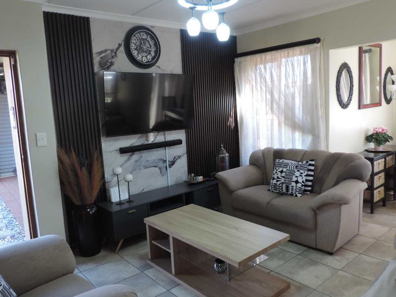 A comfortable living room featuring a modern marble-look feature wall with vertical slat detailing and tiled flooring.
