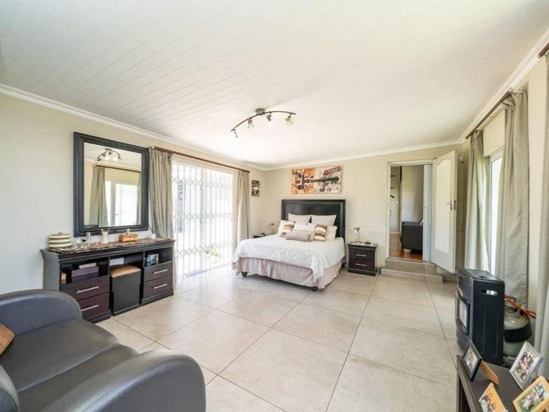 Spacious bedroom featuring large format floor tiles, a tongue and groove ceiling, and direct access to the outdoors via a sliding glass door.