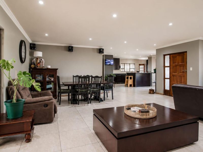 Spacious open-plan living and dining area featuring neutral tiled flooring, recessed downlighting, and seamless flow into the kitchen space.