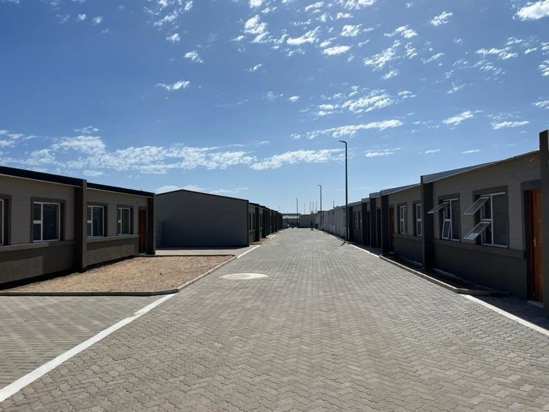 A view of a paved residential street within a townhouse complex, featuring uniform building facades and clear access paths.