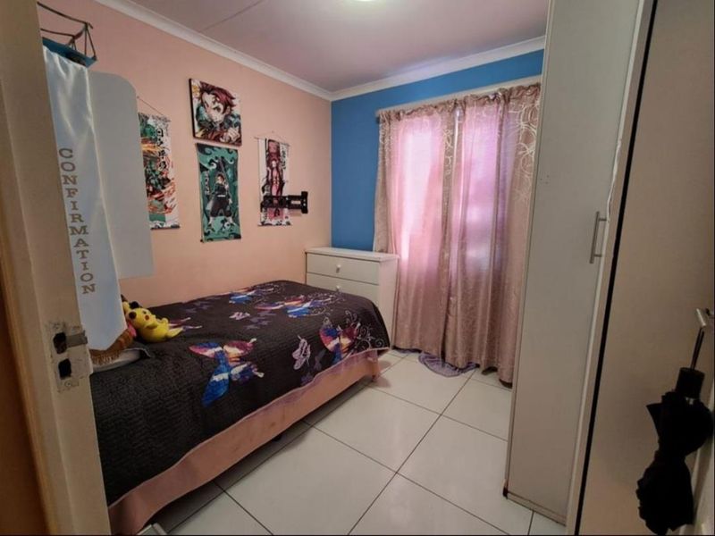 A standard bedroom featuring tiled flooring, a built-in wardrobe, and a window with curtains.