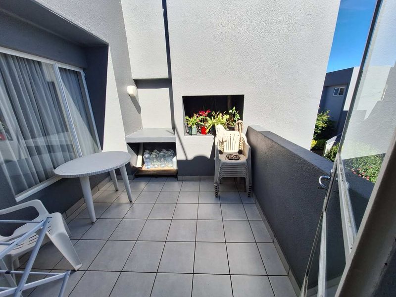 A private balcony featuring tiled flooring and a built-in braai area, providing a functional outdoor space for relaxation and entertaining.