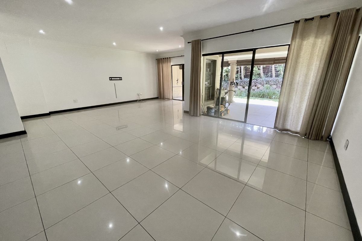 Spacious, light-filled living area featuring polished porcelain floor tiles, recessed downlighting, and large sliding glass doors providing seamless access to the outdoor patio.