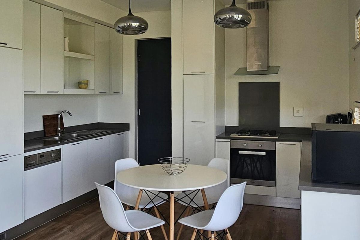 Modern kitchen featuring sleek white cabinetry, stone countertops, integrated appliances, gas hob, and stylish pendant lighting, creating a functional and contemporary cooking space.