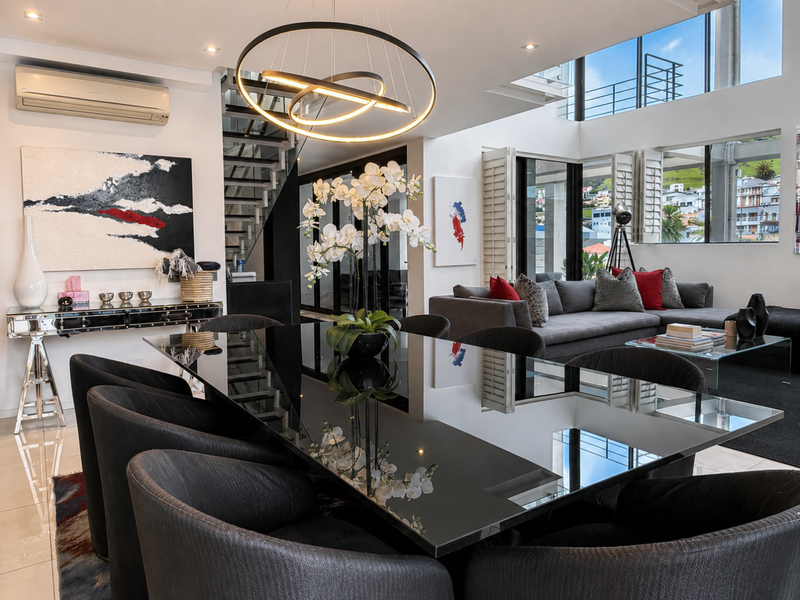 Spacious open-plan living and dining area featuring double-volume windows, modern lighting, and seamless access to outdoor spaces.