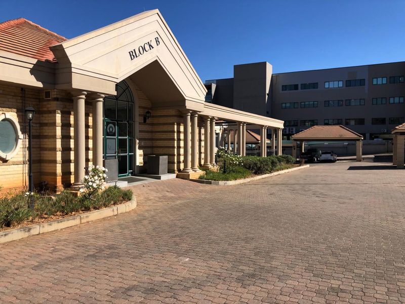 Front elevation of Block B office building featuring classical architectural columns, a paved driveway, and a covered entrance walkway.