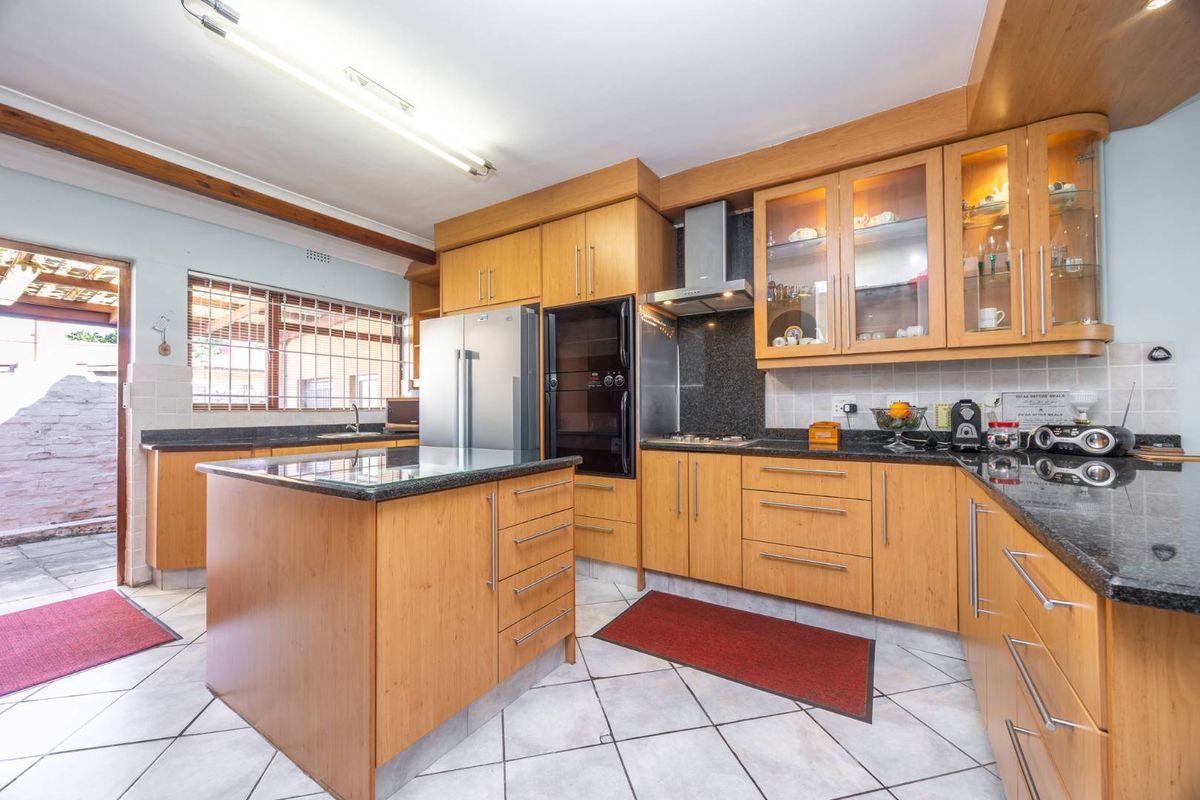 A functional kitchen featuring wooden cabinetry, granite countertops, a central island, and built-in appliances with direct access to an outdoor area.