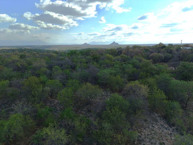 An aerial view of the expansive, naturally vegetated residential land featuring scenic mountain vistas in the distance.