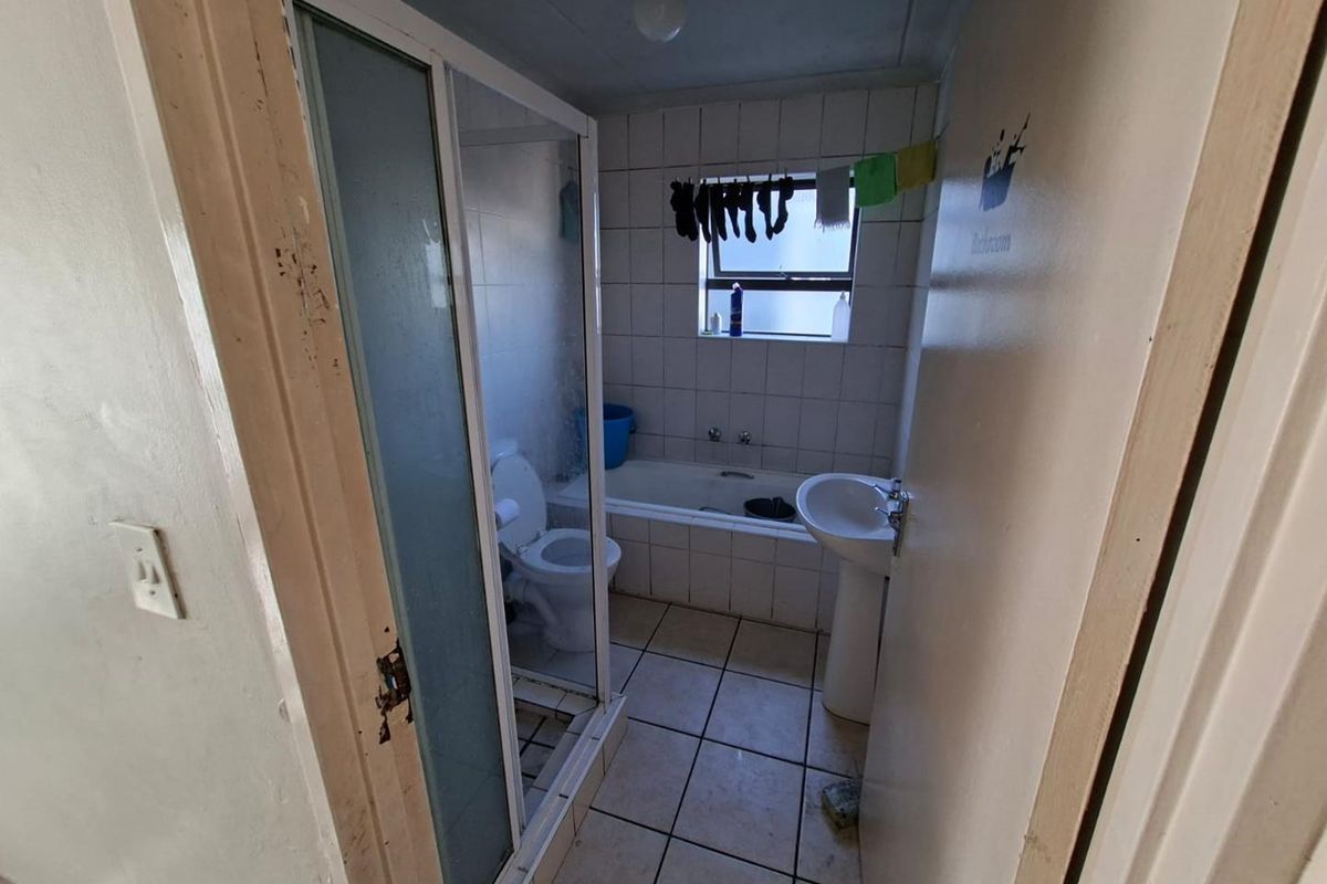 A dated bathroom featuring a shower enclosure, bathtub, pedestal basin, and toilet with tiled finishes throughout.