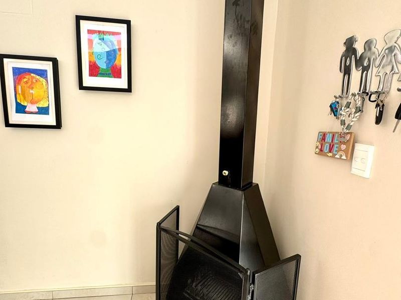 A living room area featuring a modern black freestanding fireplace and neutral tiled flooring.