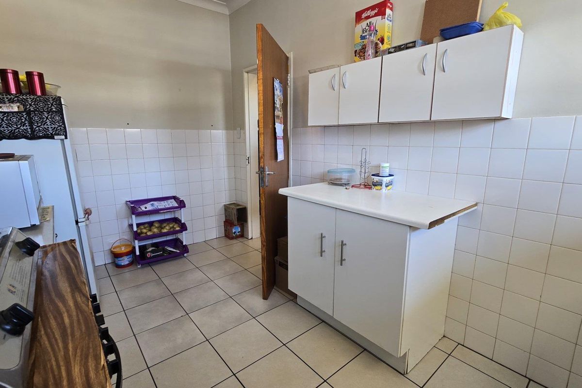 A functional kitchen area featuring white cabinetry, tiled splashbacks, and tiled flooring, providing a practical space for meal preparation.
