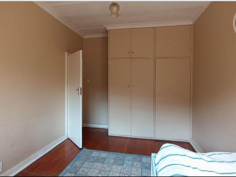 A bedroom featuring laminate flooring and ample built-in cupboard storage space.