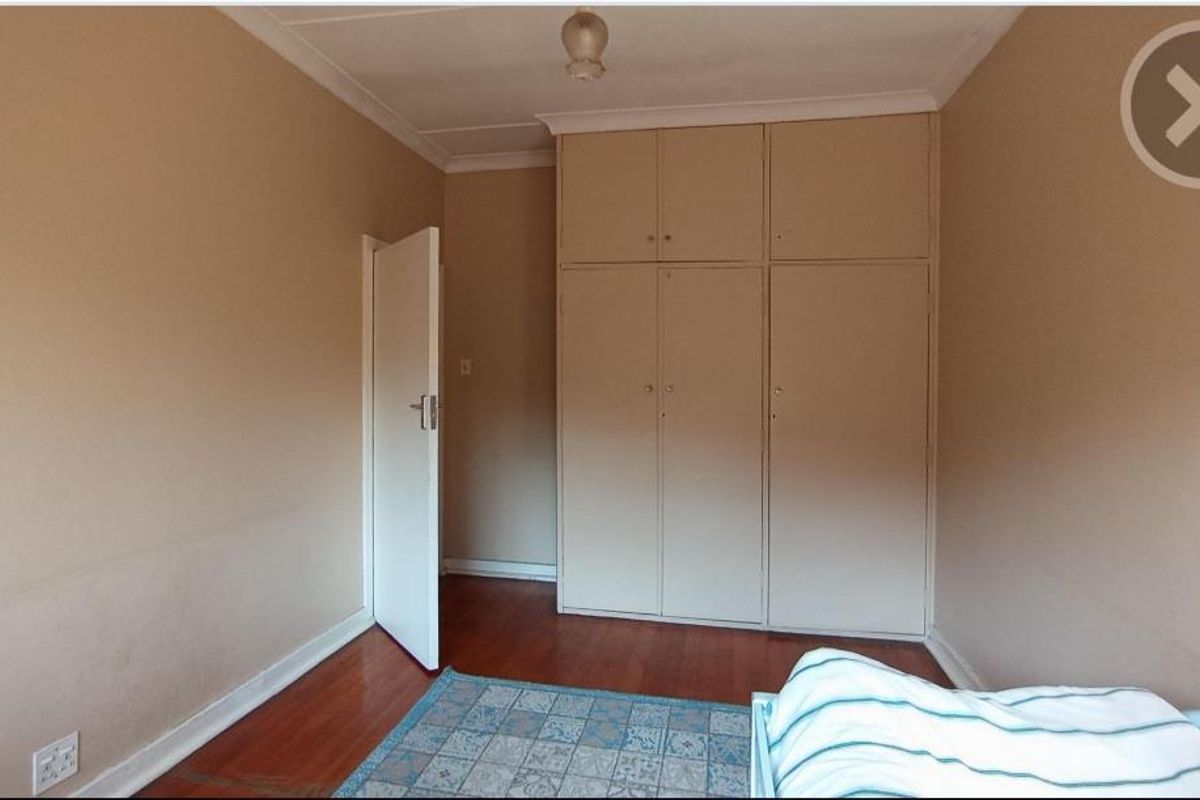 A bedroom featuring laminate flooring and ample built-in cupboard storage space.
