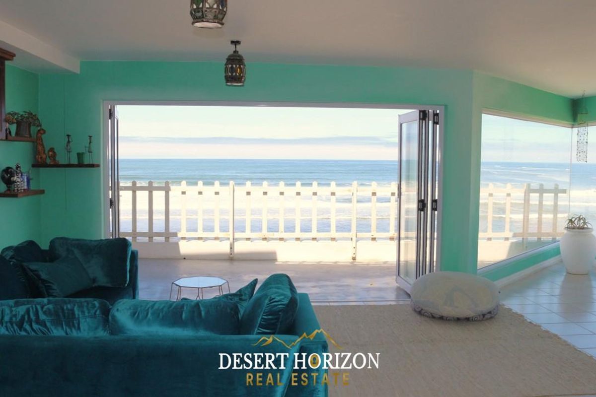 Spacious living area featuring large bi-fold doors opening onto a balcony with direct ocean views and tiled flooring.