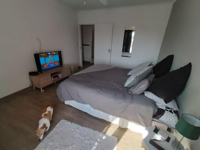 A functional bedroom featuring laminate flooring, a ceiling fan, and a neutral interior finish, providing a comfortable and well-lit sleeping space.