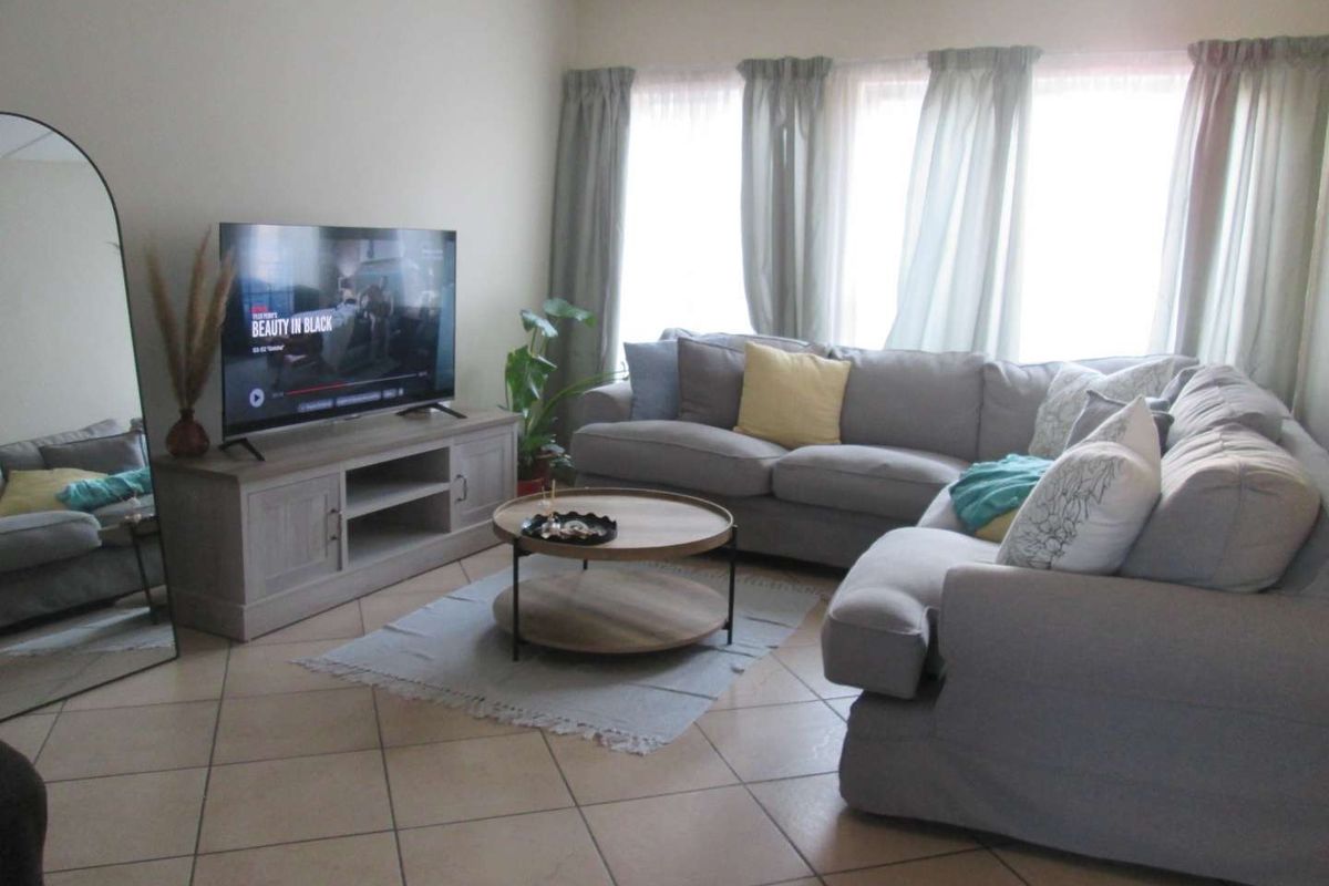 A comfortable living room featuring tiled flooring and large windows that provide ample natural light, creating a bright and inviting atmosphere.
