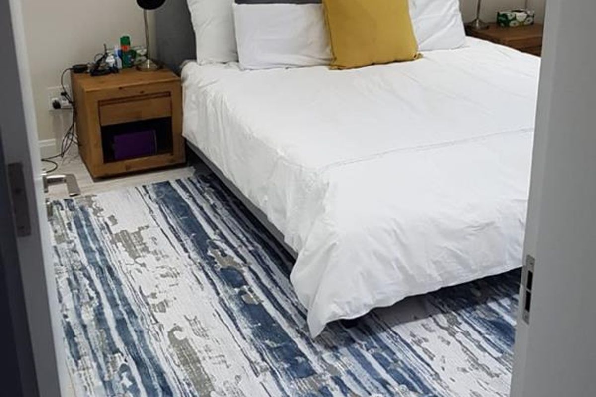 A well-maintained bedroom featuring light-toned wood-look laminate flooring and neutral wall finishes, providing a clean and comfortable living space.
