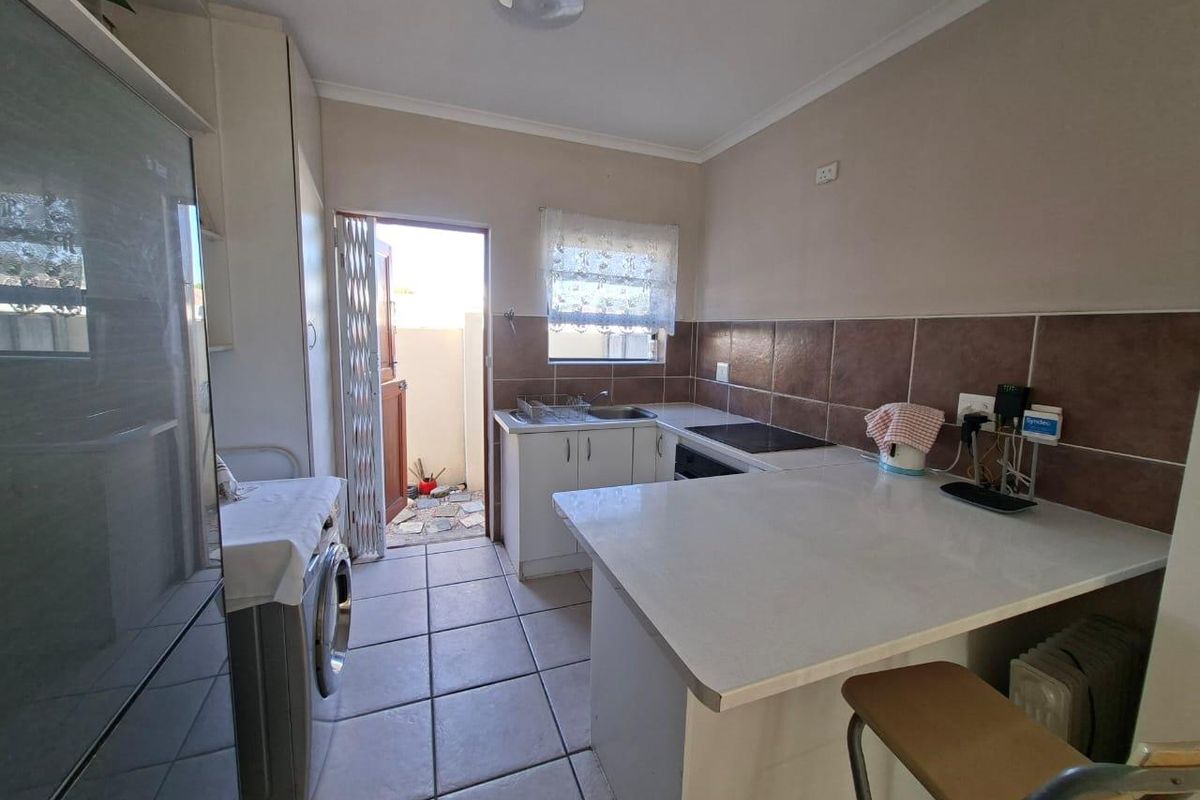 Functional kitchen featuring tiled flooring, built-in cabinetry, a breakfast counter, and direct access to an outdoor area.