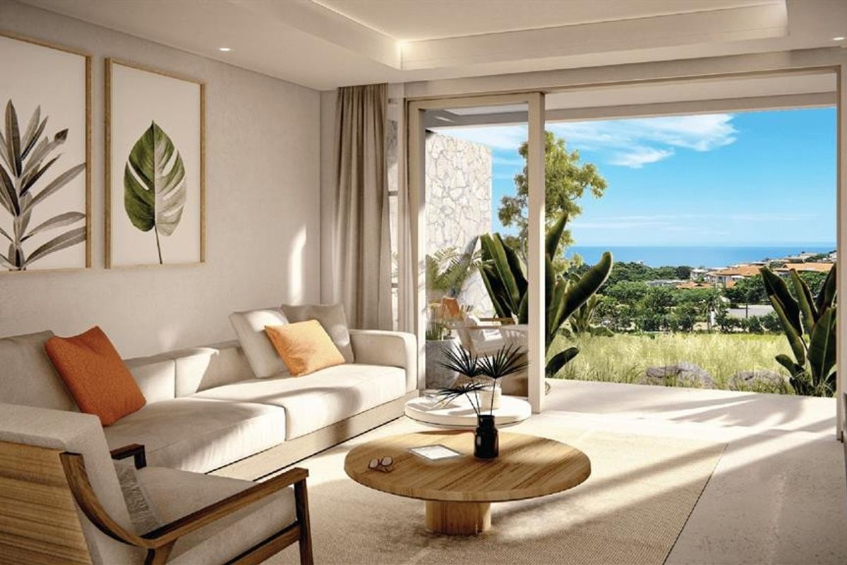Modern living room featuring recessed ceiling lighting, large sliding glass doors opening to a patio, and scenic coastal views.