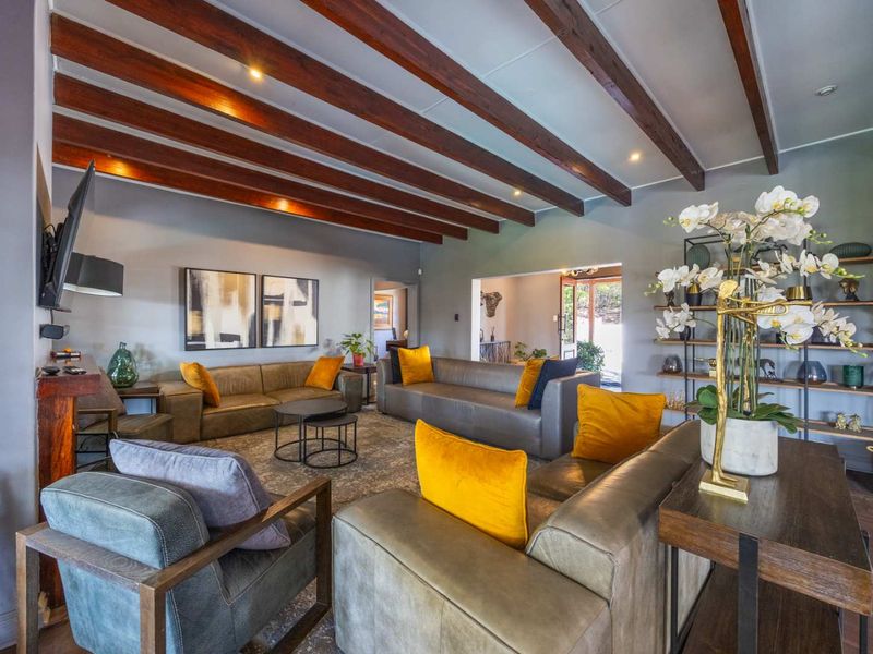 Spacious living room featuring exposed timber ceiling beams, recessed lighting, and built-in shelving, creating a warm and inviting atmosphere.