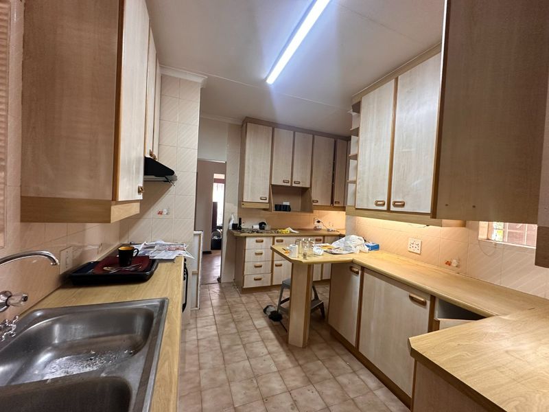 A functional kitchen featuring laminate cabinetry, tiled backsplash, and a central breakfast nook, offering a dated aesthetic ready for modernization.