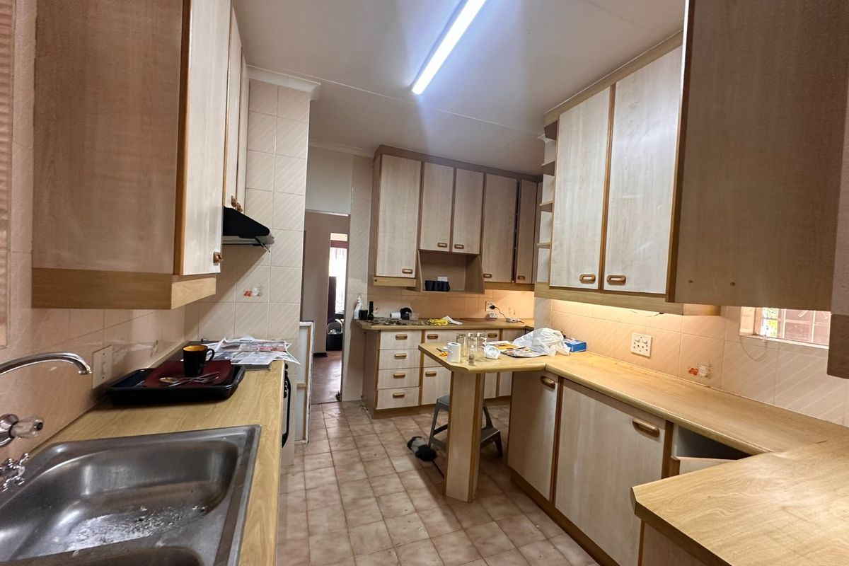 A functional kitchen featuring laminate cabinetry, tiled backsplash, and a central breakfast nook, offering a dated aesthetic ready for modernization.