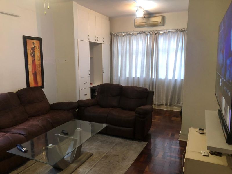A living room featuring classic parquet flooring, built-in storage cabinetry, and a wall-mounted air conditioning unit.