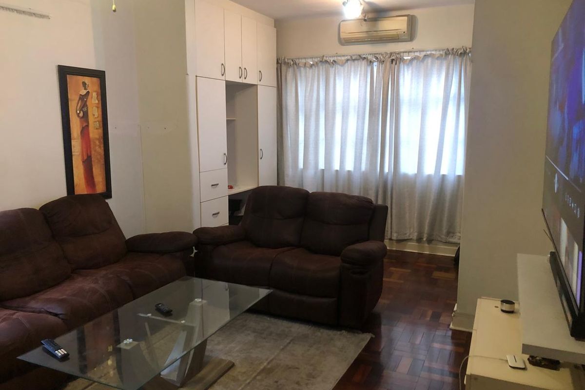 A living room featuring classic parquet flooring, built-in storage cabinetry, and a wall-mounted air conditioning unit.