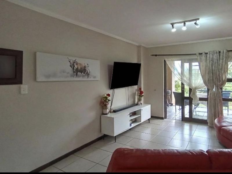 A living room featuring tiled flooring and a sliding glass door providing access to an outdoor patio area.