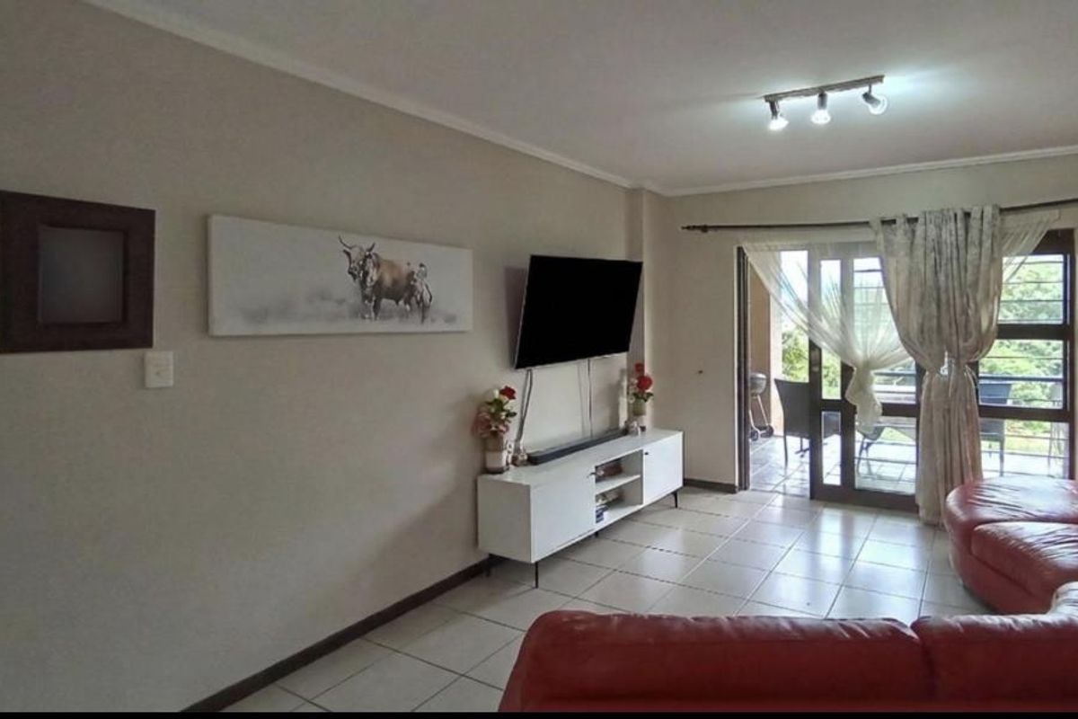 A living room featuring tiled flooring and a sliding glass door providing access to an outdoor patio area.