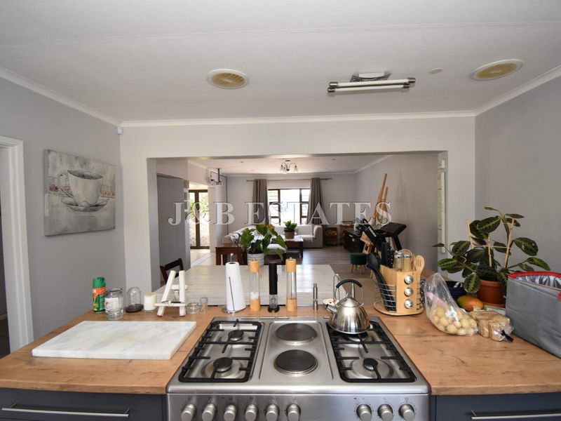 Open-plan kitchen featuring a built-in gas and electric hob, overlooking the spacious living area with neutral finishes.