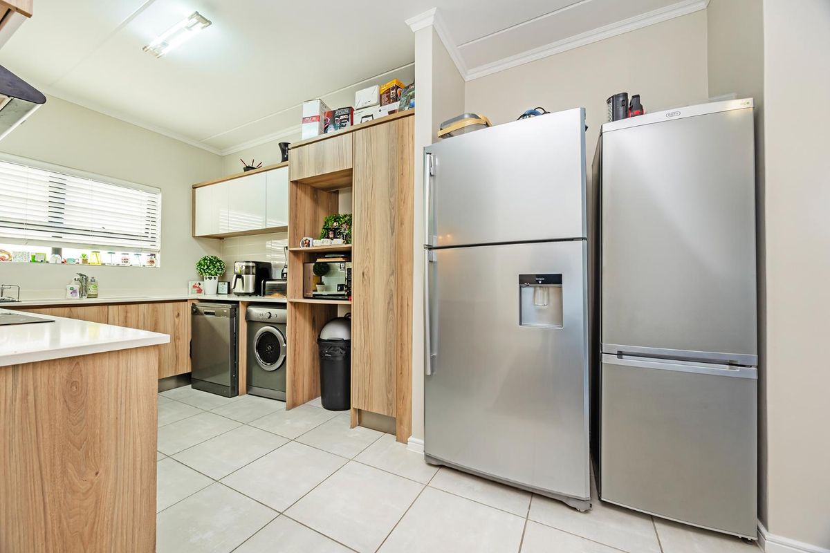 Modern kitchen featuring light wood-finish cabinetry, tiled flooring, and integrated appliance spaces, offering a clean and functional layout.