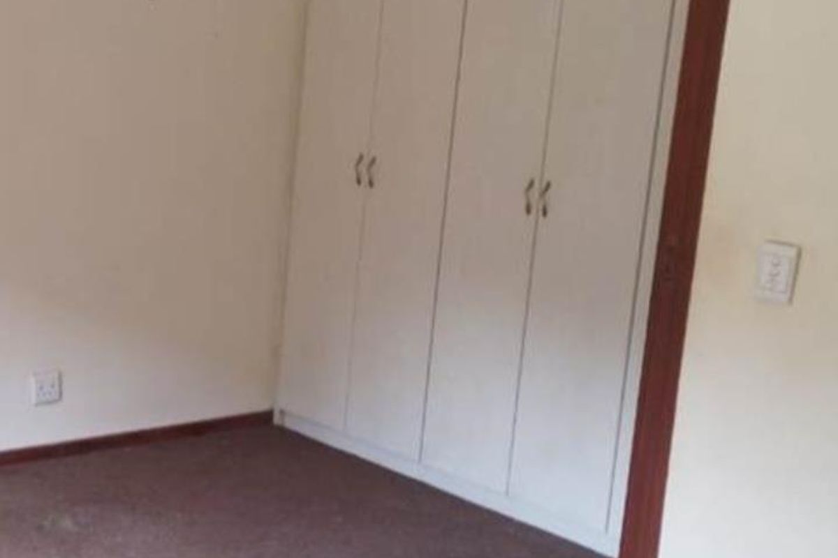 A bedroom featuring built-in cupboards and carpeted flooring.