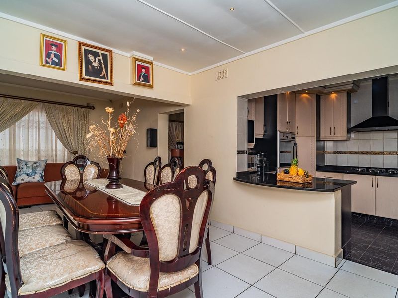 Open plan dining area adjacent to a functional kitchen featuring granite countertops, built-in cabinetry, and tiled flooring throughout.