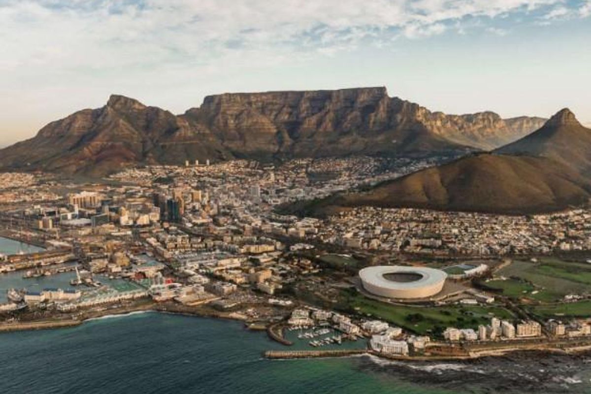 An expansive aerial view of the Cape Town coastline, featuring Table Mountain, the city bowl, and the stadium.